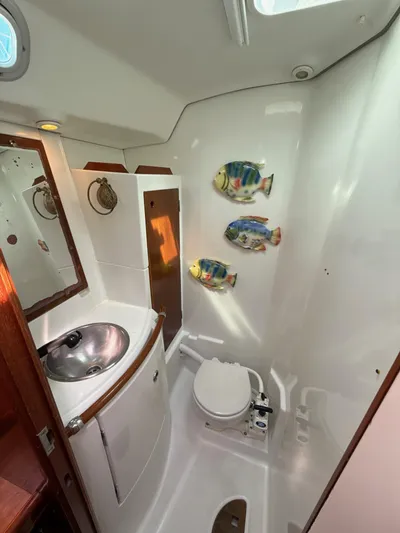 Gonzo Yacht Photos Pics Beneteau 50 yacht bathroom, 1997 model, featuring sink, toilet, and decorative fish wall art.