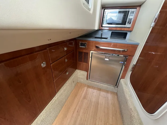  Yacht Photos Pics 2014 Formula 350 Crossover Bowrider interior kitchen with microwave, fridge, and wooden cabinets.