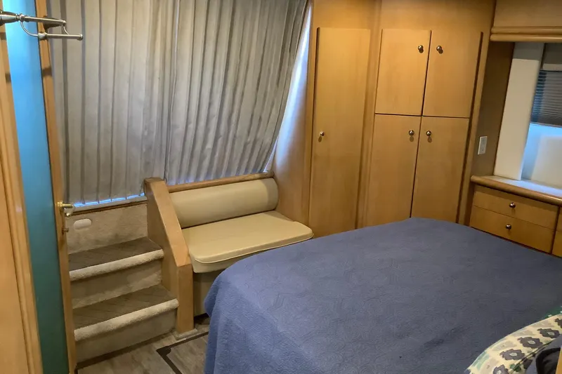 Sea Fox Yacht Photos Pics Interior of 1997 Carver 500 Cockpit Motor Yacht bedroom with bed, stairs, and wooden cabinets.