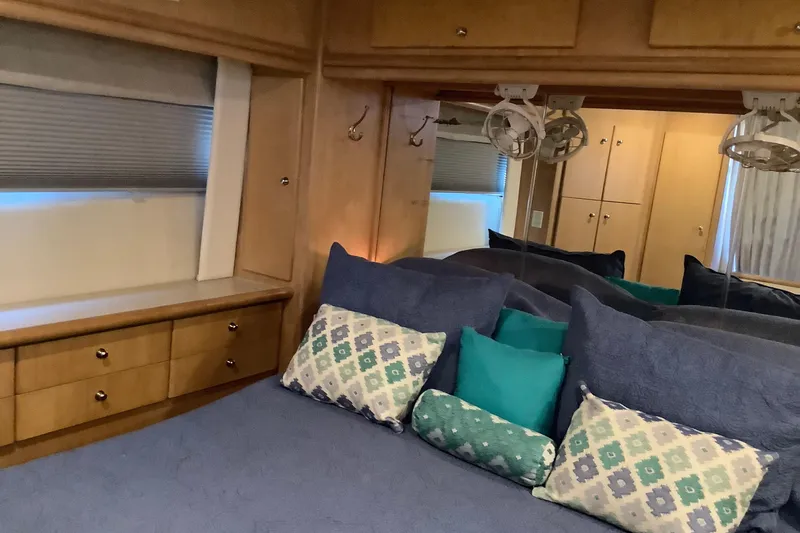 Sea Fox Yacht Photos Pics Cozy bedroom interior of 1997 Carver 500 Cockpit Motor Yacht with plush pillows and wooden cabinetry.