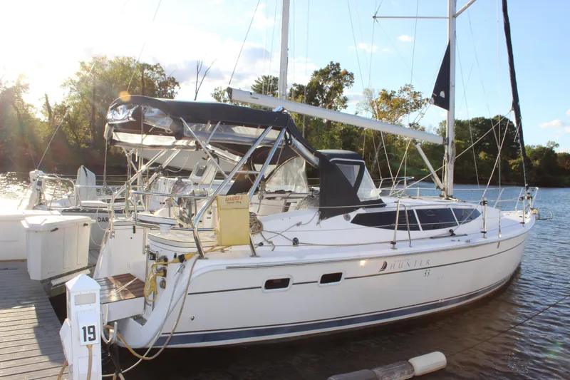  Yacht Photos Pics 2014 Hunter 33 sailboat docked on a sunny day, surrounded by trees and water.