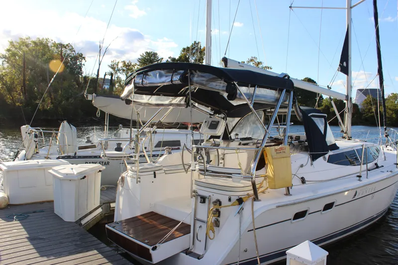  Yacht Photos Pics 2014 Hunter 33 sailboat docked by a scenic riverside with trees in the background.