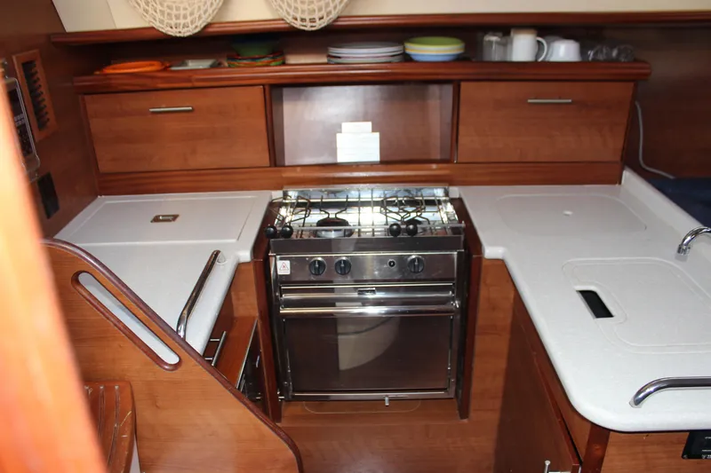  Yacht Photos Pics 2014 Hunter 33 yacht kitchen with stove, wooden cabinets, and countertop.