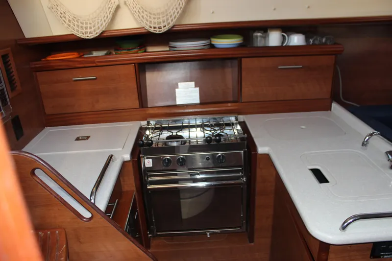  Yacht Photos Pics Compact kitchen in a 2014 Hunter 33 sailboat with stove, sink, and wooden cabinetry.