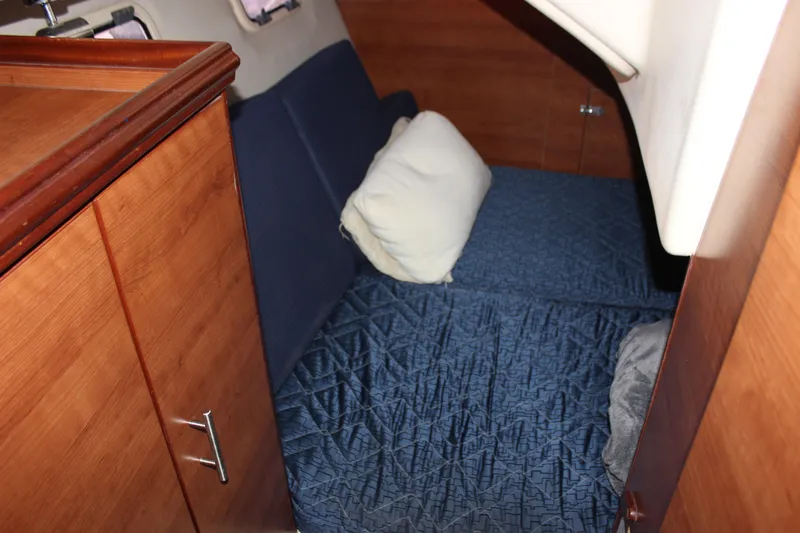  Yacht Photos Pics Cozy cabin interior of 2014 Hunter 33 sailboat with blue bedding and wooden cabinetry.