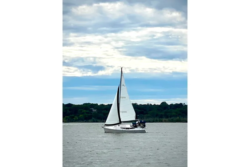  Yacht Photos Pics 2014 Hunter 33 sailboat on a calm lake under a cloudy sky.