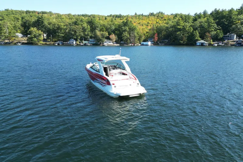  Yacht Photos Pics 2024 Formula 330 Crossover Bowrider on a serene lake with lush green shoreline.