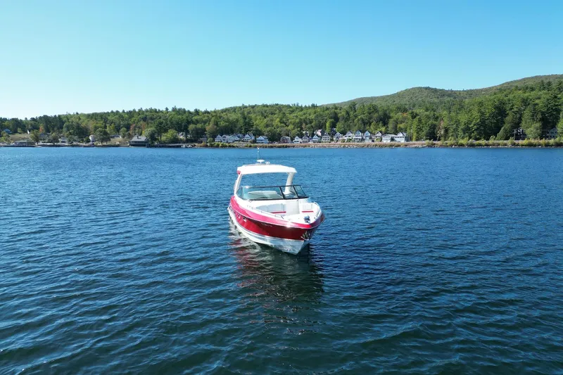  Yacht Photos Pics 2024 Formula 330 Crossover Bowrider on a serene lake with forested shoreline.