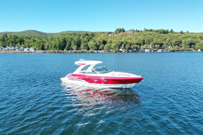  Yacht Photos Pics 2024 Formula 330 Crossover Bowrider on a serene lake with forested shoreline.