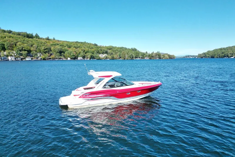  Yacht Photos Pics 2024 Formula 330 Crossover Bowrider on a serene lake with lush green shoreline.