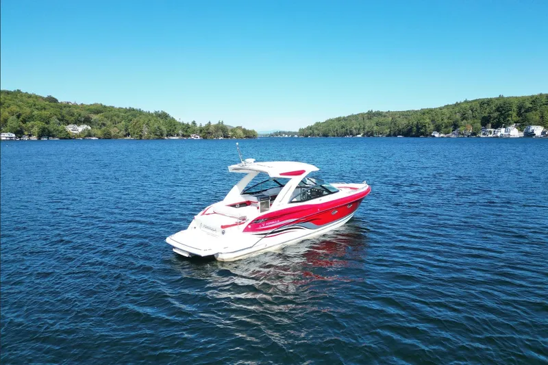  Yacht Photos Pics 2024 Formula 330 Crossover Bowrider on a serene lake with lush green shoreline.