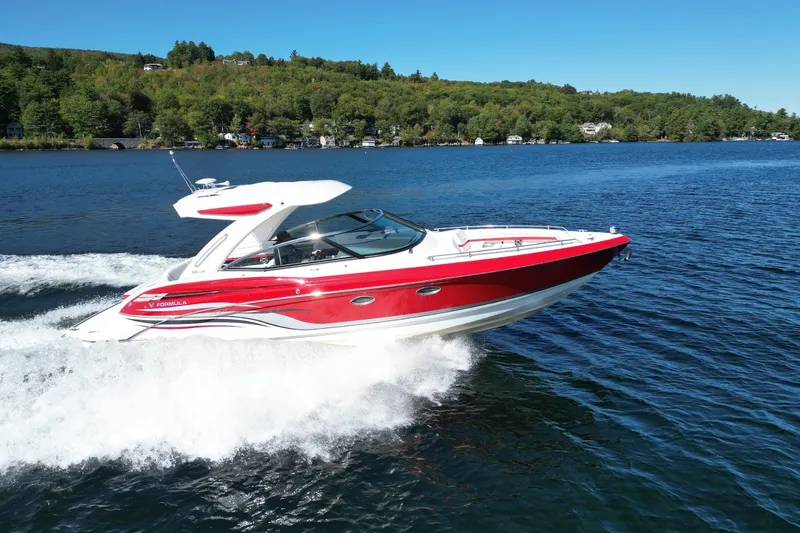  Yacht Photos Pics 2024 Formula 330 Crossover Bowrider cruising on a scenic lake with lush green shoreline.