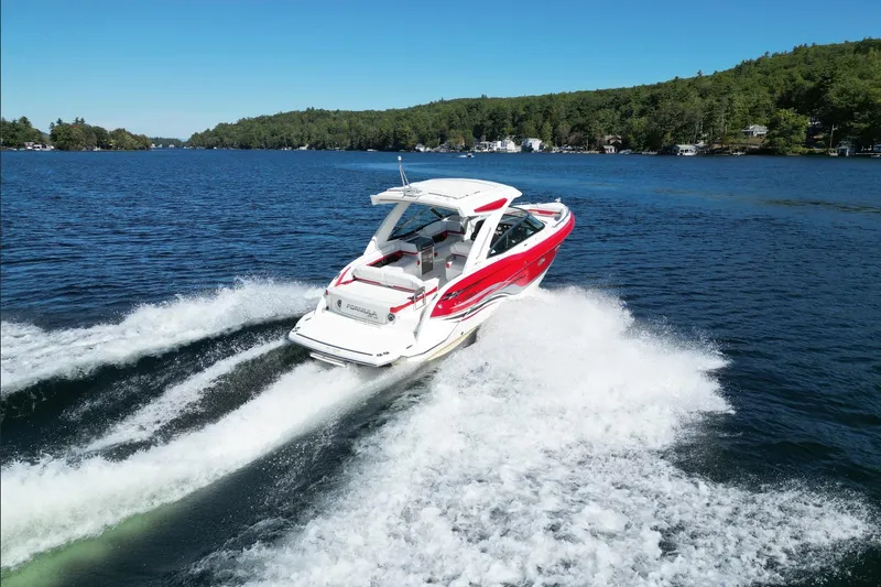  Yacht Photos Pics 2024 Formula 330 Crossover Bowrider cruising on a scenic lake with lush green shoreline.