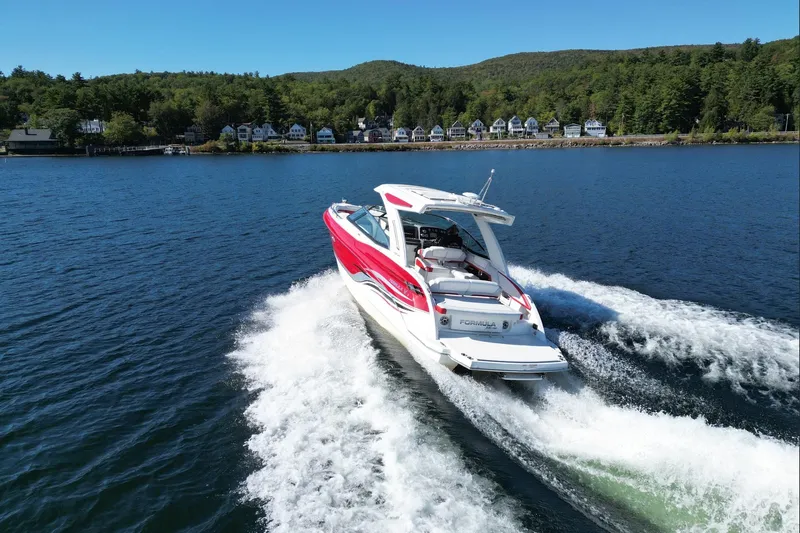  Yacht Photos Pics 2024 Formula 330 Crossover Bowrider cruising on a scenic lake with forested shoreline.