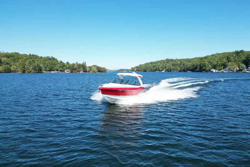  Yacht Photos Pics 2024 Formula 330 Crossover Bowrider cruising on a scenic lake under clear blue skies.