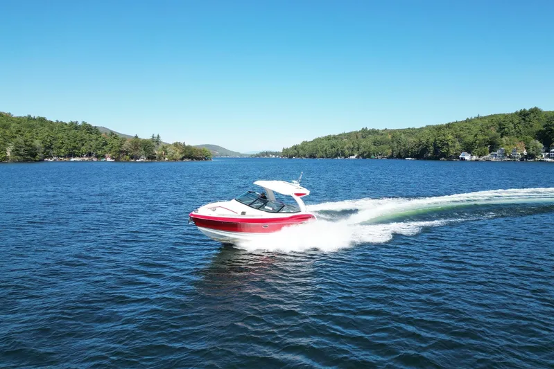  Yacht Photos Pics 2024 Formula 330 Crossover Bowrider cruising on a scenic lake under clear blue skies.