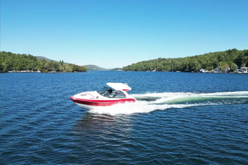  Yacht Photos Pics 2024 Formula 330 Crossover Bowrider cruising on a scenic lake under clear blue skies.