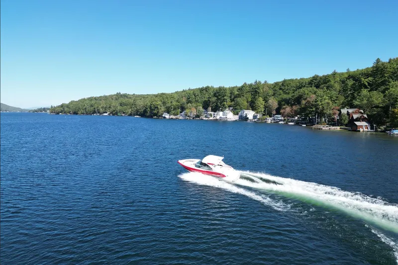  Yacht Photos Pics 2024 Formula 330 Crossover Bowrider cruising on a scenic lake under clear blue skies.