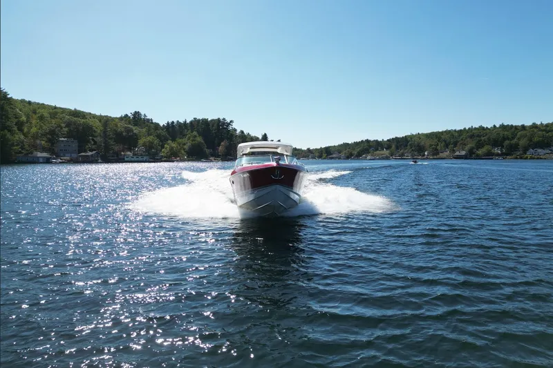  Yacht Photos Pics 2024 Formula 330 Crossover Bowrider cruising on a scenic lake under clear blue skies.