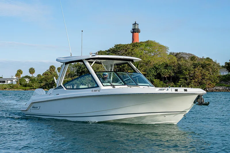  Yacht Photos Pics 2021 Boston Whaler 280 Vantage boat cruising near a lighthouse on a sunny day.