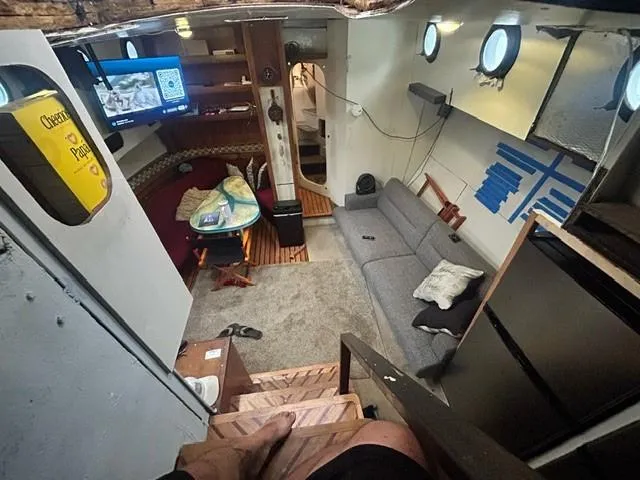 Dauntless Yacht Photos Pics Cozy boat interior with sofa, dining area, TV, and portholes, custom model from 1990.