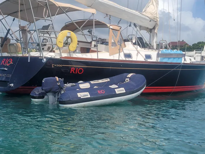 Rio Yacht Photos Pics Tartan 4300 sailboat from 2008 with a dinghy, anchored in clear blue water.