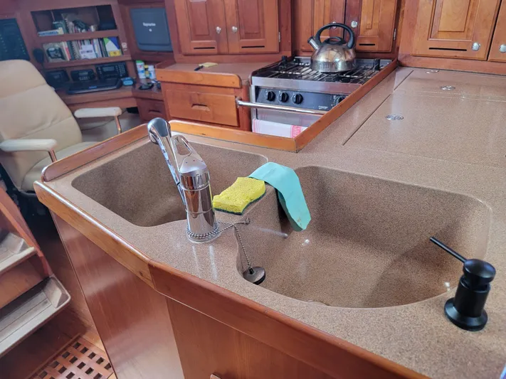 Rio Yacht Photos Pics Interior of 2008 Tartan 4300 yacht kitchen with sink, stove, and wooden cabinetry.