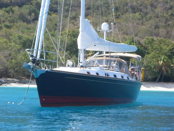 Rio Yacht Photos Pics Tartan 4300 sailboat from 2008 anchored in clear blue water near a tropical shoreline.