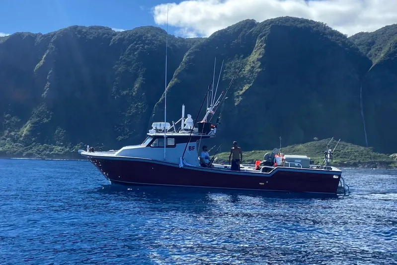 Yacht Photos Pics Custom Hoku 40 boat on blue water with lush green mountains in the background.