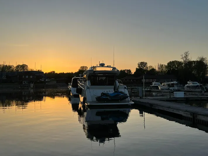  Yacht Photos Pics 2018 Carver C52 Coupe yacht docked at sunset, reflecting on calm water.