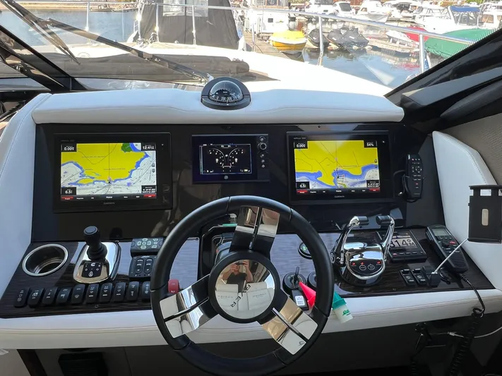  Yacht Photos Pics Control panel of a 2018 Carver C52 Coupe yacht with navigation screens and steering wheel.