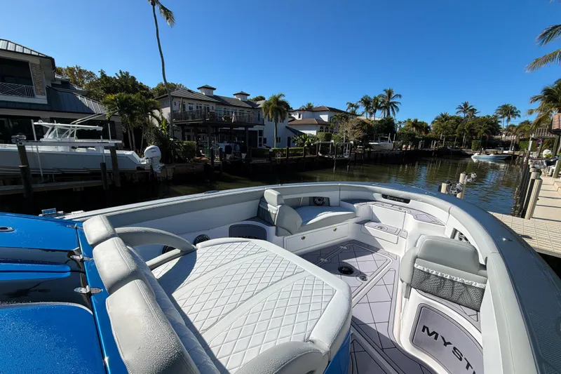  Yacht Photos Pics 2023 Mystic Powerboats M3800 docked in a scenic waterfront setting with palm trees.