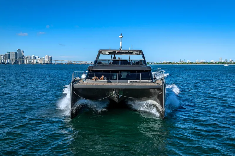  Yacht Photos Pics 2026 Sunreef 60 Power yacht cruising in blue ocean near city skyline.