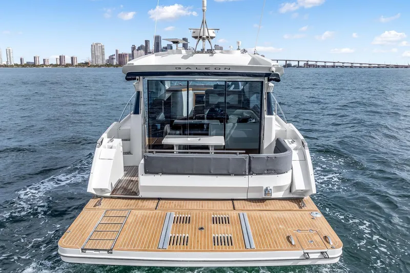  Yacht Photos Pics 2018 Galeon 430 HTC yacht cruising on open water with city skyline backdrop.