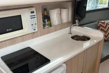  Yacht Photos Pics Compact kitchen in 2023 Hanover 377 with microwave, sink, and stove.