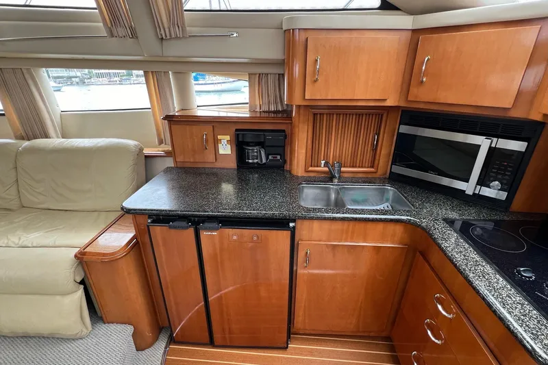  Yacht Photos Pics 2003 Carver 444 Cockpit Motor Yacht kitchen with wood cabinetry, granite countertops, and modern appliances.