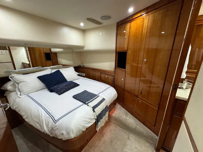  Yacht Photos Pics Luxurious bedroom in 2004 Bertram 510 Convertible yacht with wood cabinetry and cozy bedding.