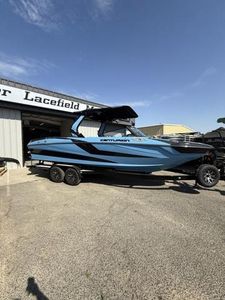 2025 Centurion Fe25 boat in blue, parked on a trailer outside a dealership.