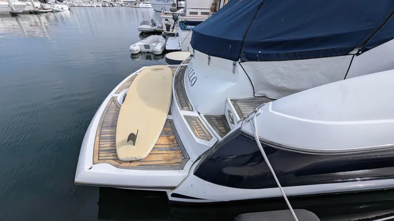 Cavallo Yacht Photos Pics 2004 Sunseeker Portofino yacht with surfboard on deck, docked in marina.