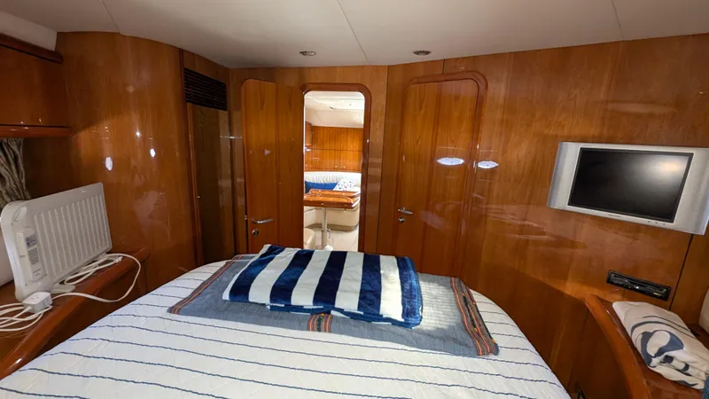 Cavallo Yacht Photos Pics Interior of 2004 Sunseeker Portofino yacht cabin with bed, TV, and wooden paneling.