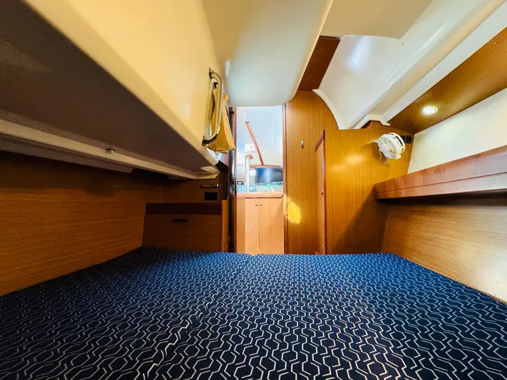 La Dauphine Yacht Photos Pics Interior cabin of 2007 Jeanneau Sun Odyssey 36i sailboat, featuring wood paneling and blue bedding.