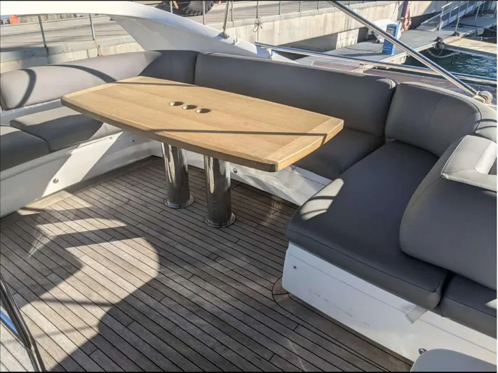  Yacht Photos Pics Flybridge seating area on 2014 Princess 52 yacht with wooden table and cushioned seats.