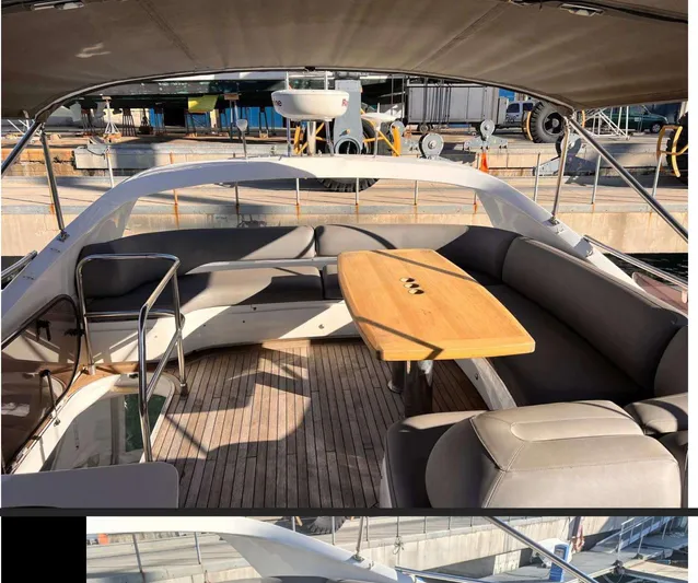  Yacht Photos Pics Flybridge seating area on 2014 Princess 52 yacht with wooden table and cushioned seats.