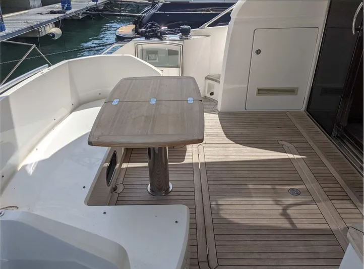  Yacht Photos Pics Flybridge deck of 2014 Princess 52 yacht with wooden table and seating area.