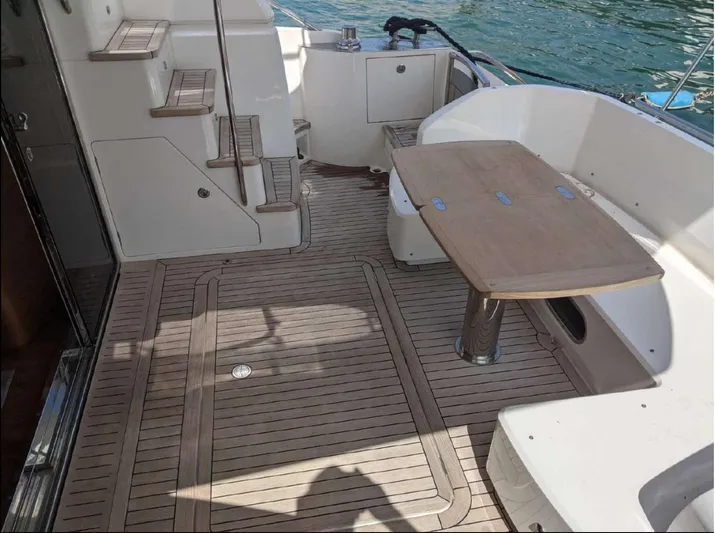  Yacht Photos Pics Flybridge yacht deck with wooden table, steps, and water view; Princess 52, 2014 model.