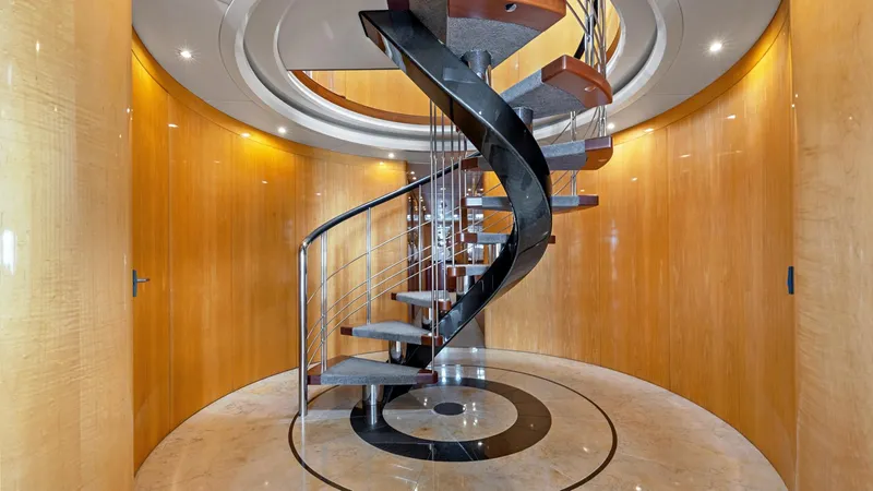 My Spirit Yacht Photos Pics Luxurious spiral staircase inside 2005 New Zealand Yachts Wave Piercer, featuring elegant wood paneling.