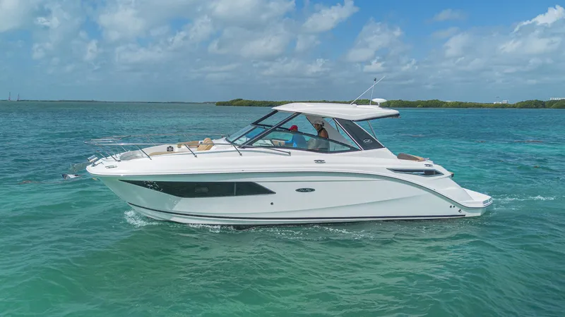 White Kraken Yacht Photos Pics 2023 Sea Ray Sundancer 320 cruising on clear blue waters under a partly cloudy sky.