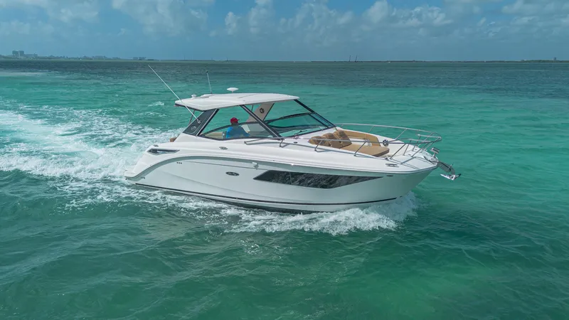 White Kraken Yacht Photos Pics 2023 Sea Ray Sundancer 320 cruising on turquoise ocean waters under a clear blue sky.