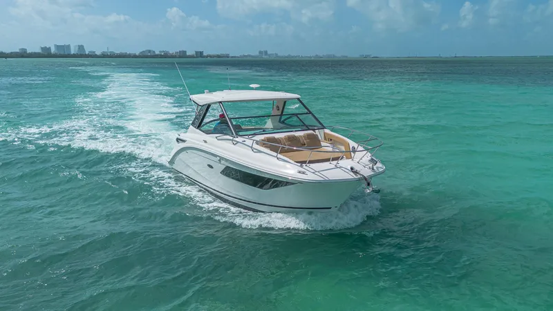 White Kraken Yacht Photos Pics 2023 Sea Ray Sundancer 320 cruising on turquoise ocean waters under a clear sky.