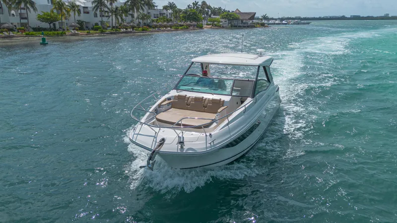 White Kraken Yacht Photos Pics 2023 Sea Ray Sundancer 320 cruising on a sunny day near a tropical shoreline.